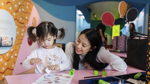 Young woman and little girl at craft table with stickers