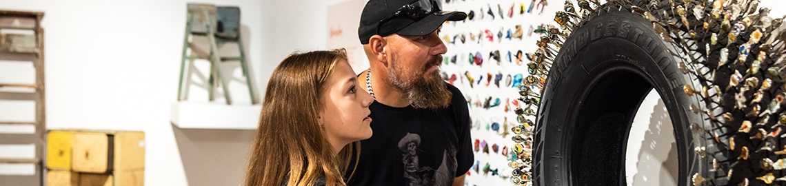 Man and girl closely inspect an exhibit inside the Pine Rivers Heritage Museum