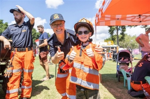 Boy trying on emergency services uniform with worker