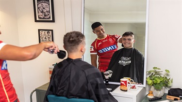 Isaiya Katoa giving a haircut to a smiling young local.