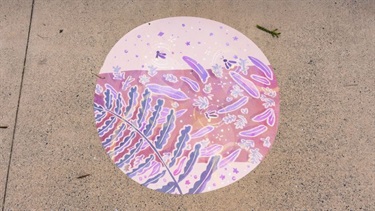 Close‑up of a circular vinyl artwork with pink and purple patterns installed on a concrete surface.