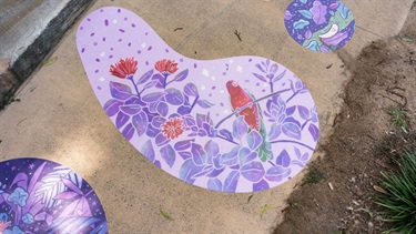 Tear‑shaped vinyl artwork with purple floral designs applied to a pathway.