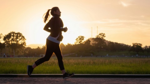 Person jogging alongside grassy field