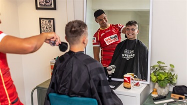 Isaiya Katoa giving a haircut to a smiling young local.