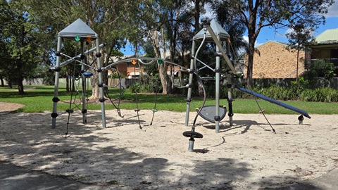 Kids playground with slide and climbing structures on sand.