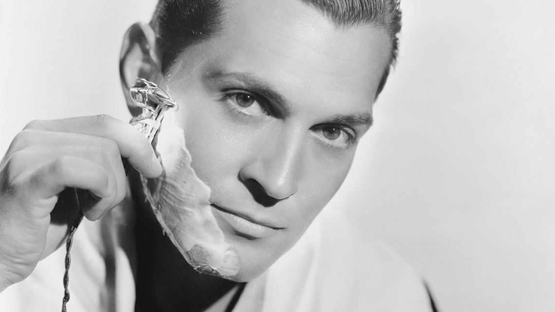 Black and white image of man shaving his face