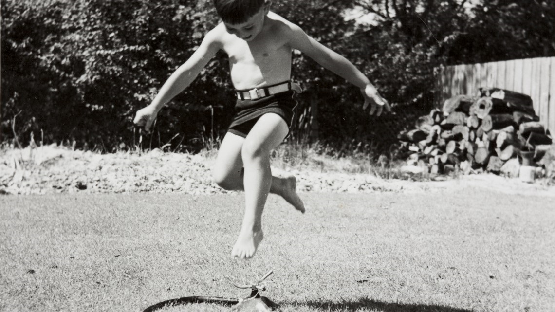 Child jumping over sprinkler