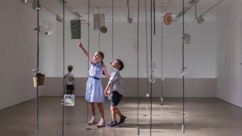 Boy and girl in art display of hanging rope