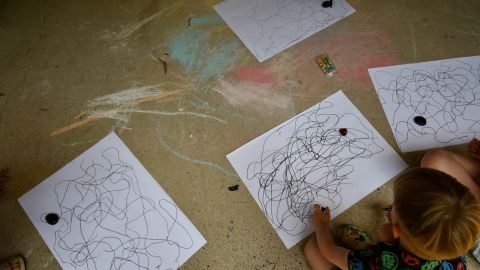 Kids drawing squiggly lines in black ink