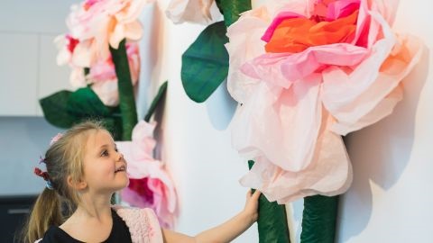 Young girl looking at giant paper flower