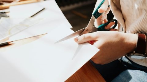 Person cutting white paper with scissors