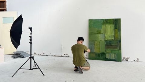 Photographer crouching in front of artwork to take a photo