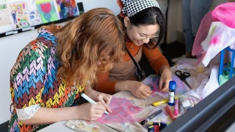 Two women working on fabric on a table