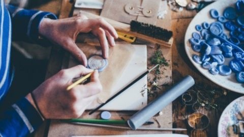 Artist's hands sculpting round disc