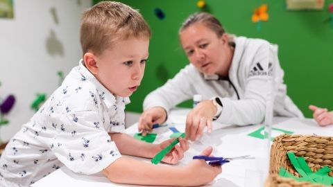 A boy and an adult crafting with green wall background