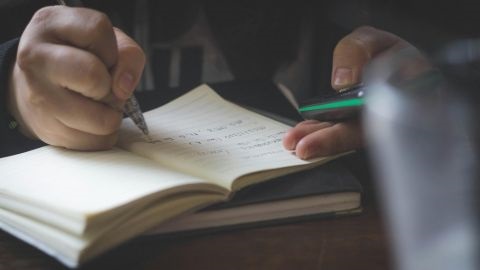Person writing in a journal with dark background