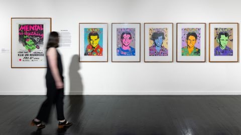 Person walking past posters on a gallery wall