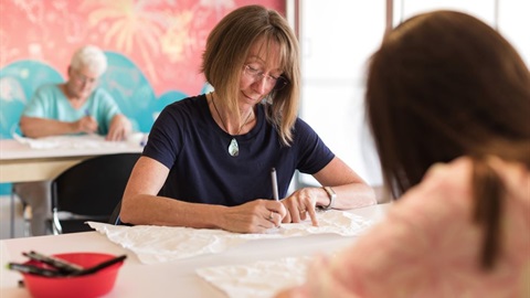 Three women sitting at desks and drawing