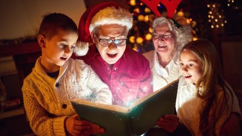 Man and woman dressed for Christmas reading to two children