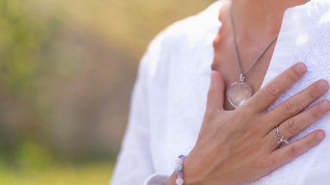 Woman in white shirt with hand on heart