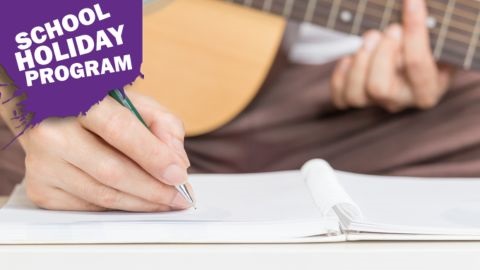 Person holding guitar and writing in notebook