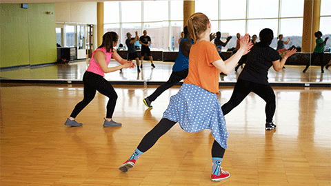 A group of people dancing in front of a mirror.