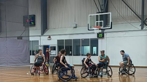 a group of people in wheelchairs on a basketball court playing wheelchair basketball