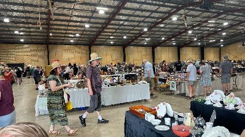 Many stalls are layout around in indoor venue. People are walking around browsing the markets.