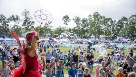 A woman in a fairy costume performs on stage in front of children.