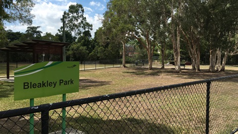Fenced off dog park with a green sign that reads 'Bleakley Park'.