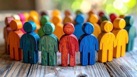 Coloured wooden figures are lined up in a row on a table.