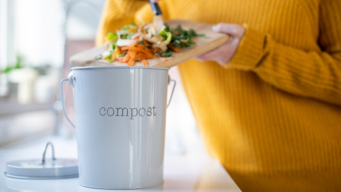 woman adding kitchen scraps to compost bin