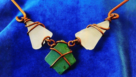Bronze metal wire encasing three pieces of coloured glass.