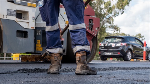 Generic photo of road worker smoothing out fresh asphalt