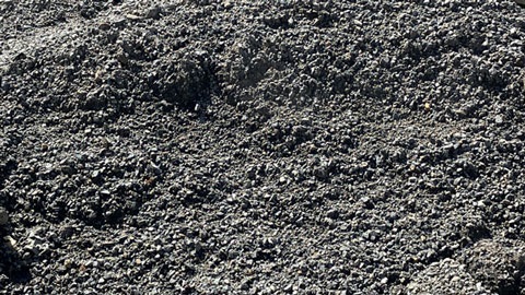 Close-up view of a rough, dark gravel surface with uneven texture.