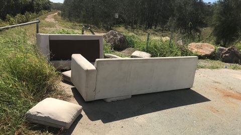 Illegal dump of a couch in bushland