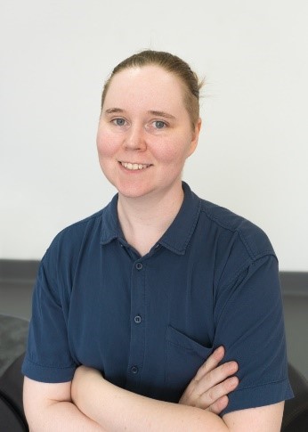 Lauren Edmonds, a while women in a blue shirt smiling at the camera with her arms crossed.
