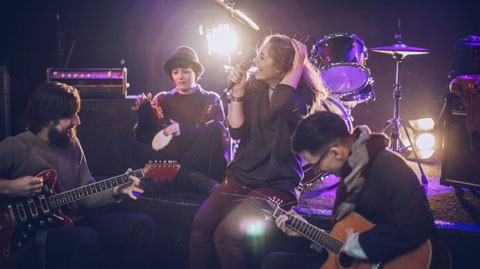 Group of musicians sitting around playing instruments and singing