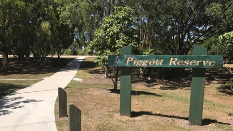 Dark green timber sign with gold writing that reads 'Piggott Reserve'.